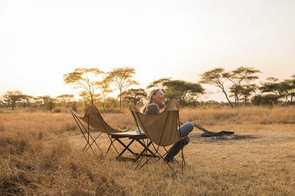 Two guests enjoying sundowner drinks in the Serengeti at sunset.