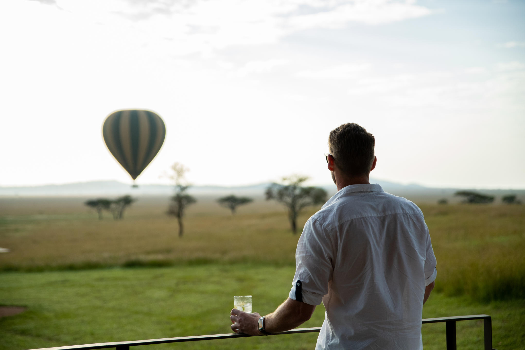 A group of three travelers and their safari guide enjoy a coffee break and snacks in front of their vehicle near a river at Londolozi.